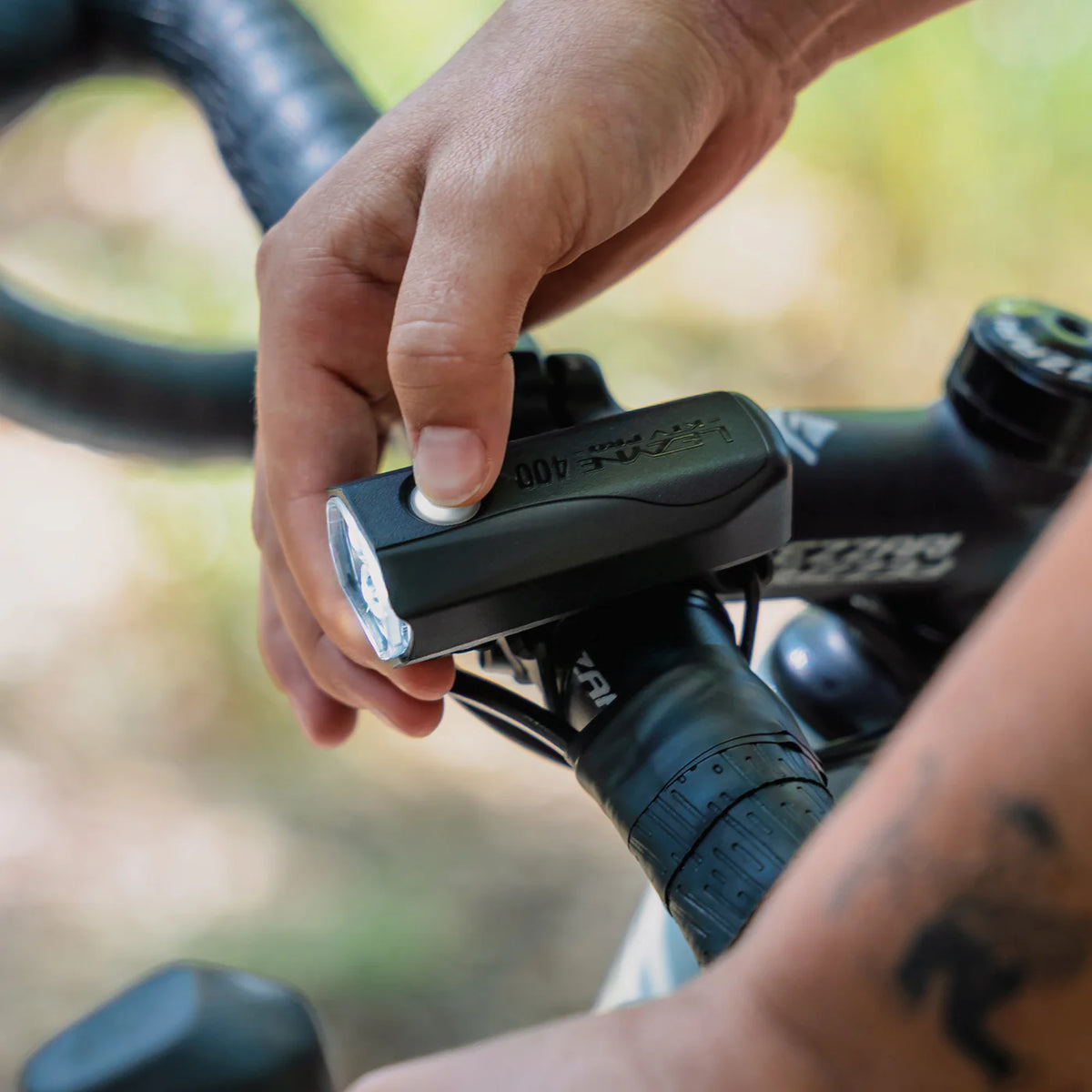 Hand adjusting the KTV Drive Pro 400 front light mounted on a bicycle handlebar.