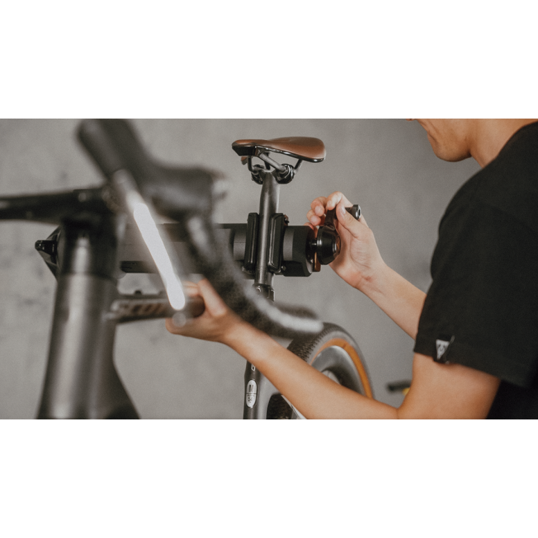 Topeak bike work stand 45kg being used for bike maintenance with a mechanic adjusting the bike components.