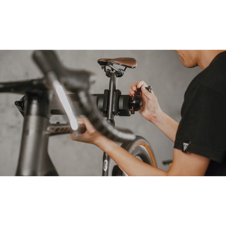 Topeak bike work stand 45kg being used for bike maintenance with a mechanic adjusting the bike components.
