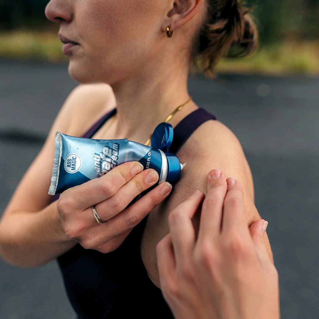 Woman applying Ass Magic anti chafe cream for athletes on her shoulder during an outdoor workout.