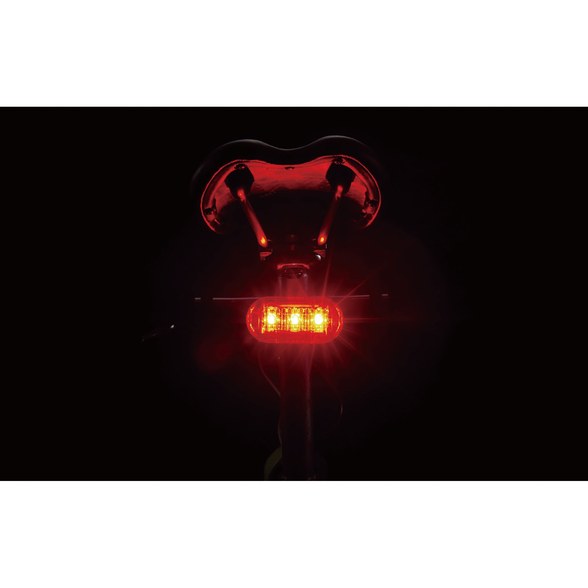 CatEye Omni 3 rear light mounted on a bicycle saddle, glowing red with strong visibility.