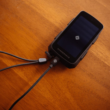 USB C charging cable for Hammerhead Karoo connected to a Hammerhead device on a wooden surface.