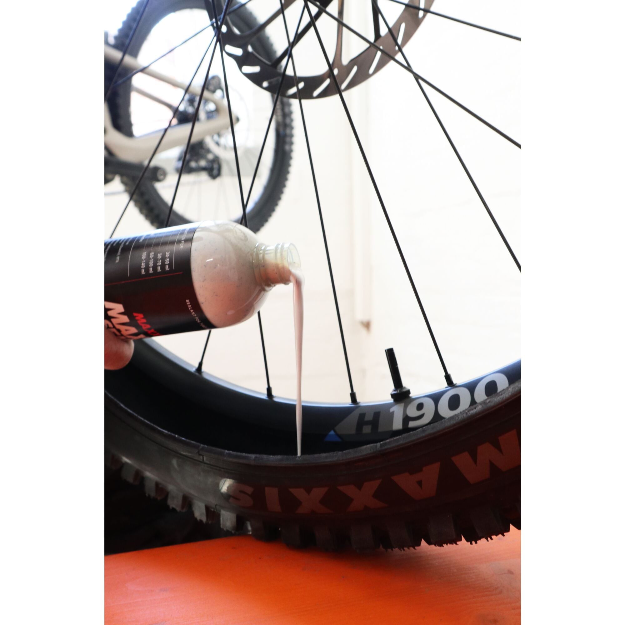 Applying Maxxis tubeless tyre sealant to a mountain bike tyre for optimal performance.