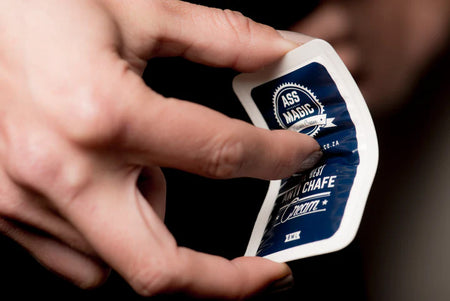 Hand holding an Ass Magic chamois cream sachet from the travel chamois cream sachets pack.