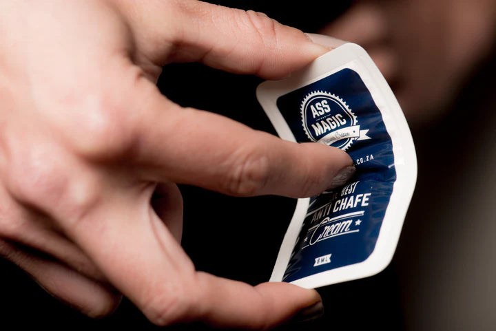 Hand holding an Ass Magic chamois cream sachet from the travel chamois cream sachets pack.
