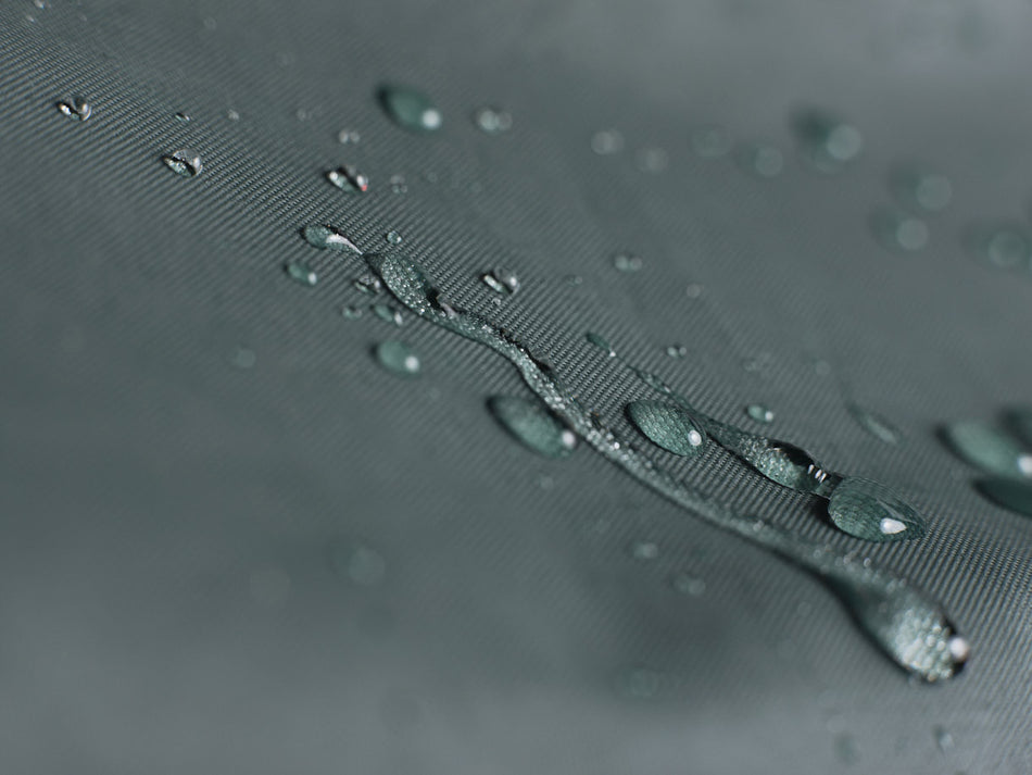 Close-up of water droplets on a waterproof bicycle cover forest green fabric.