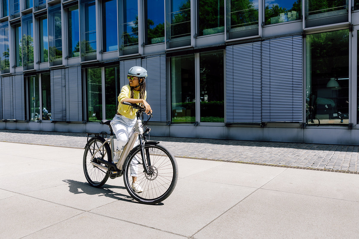 Woman riding an urban wired bike tyre in a modern city setting with buildings and sunlight.