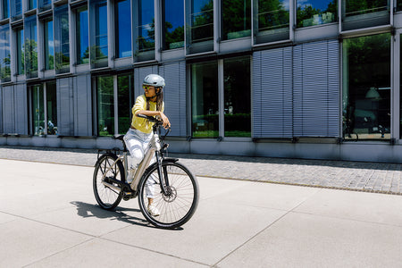 Woman riding an urban wired bike tyre in a modern city setting with buildings and sunlight.