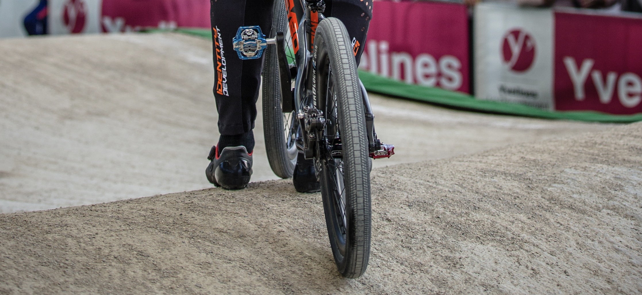Close-up of a rider's foot on a BMX bike with a Tioga Powerblock 20 inch BMX wired tyre on a dirt track.