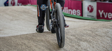 Close-up of a rider's foot on a BMX bike with a Tioga Powerblock 20 inch BMX wired tyre on a dirt track.
